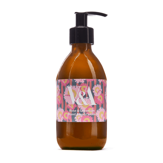 A brown glass bottle with a black pump and a pink label. Printed on the label are a floral pattern and the V&A logo in white.